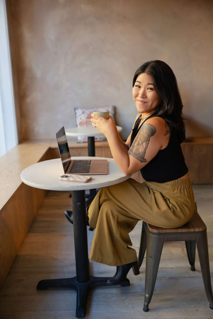 Virtual Assistant sitting in Patcha Collective Coffee Shop in Ballard, with open lap top, holding a cappuccino.